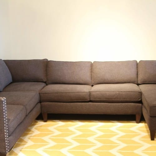 this mid-century modern charcoal sectional appears cold and drab because of the low back and straight lines. the chevron flatweave rug adds a vibrant pop of color and sets the stage for accents.