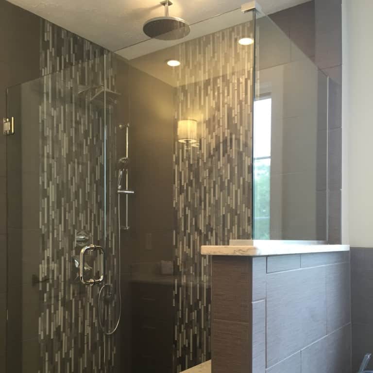 a common material like glass mosaic tile can be given an instant face lift simply by changing its orientation. we framed out the shower fixtures and gave the back wall the same vertical stripe to turn the shower into a showpiece.