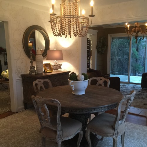 An elegant and intimate dining room is created by playing reclaimed wood and distressed black painted furniture pieces off of more polished finishes like the chandelier and wallpaper
