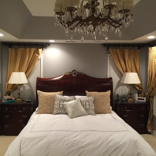 If you have pieces that you love and have really invested money in, simply updating paint and bedding can change the entire feel of a room. A dark wood bedroom suite and gold window treatments are lightened by new white custom bedding and a custom paint mix of metallic silver on the walls