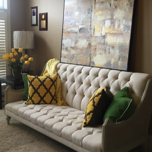 Greens and yellows accent a gorgeous tufted loveseat in Shawnee’s office, providing a chic twist on guest seating