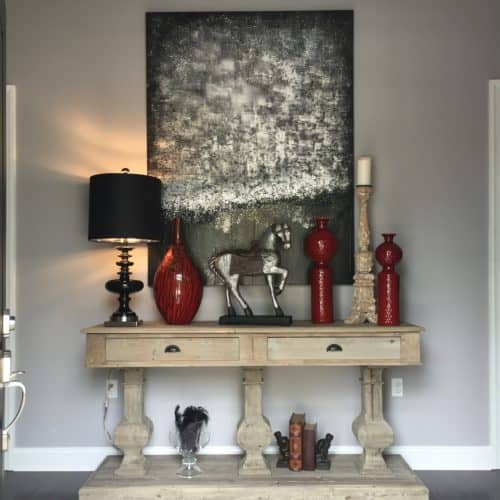 Pairing a reclaimed wood three-corbel console table with modern art and a little bit of glam makes for a striking entry. Add in splashes of red for a breathtaking statement to set the tone for the rest of a home