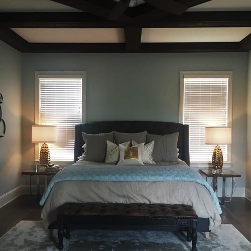 Removing the large, dark wood sleigh bed and replacing it with an upholstered bed in a washed slate-colored fabric set the tone for the new master bedroom. Now, with layers of rich bedding in calming hues of blues, cream, and gold, the room feels masculine yet soft